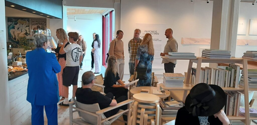 Grupp av besökare som minglar i ett ljust museirum under vernissagen.